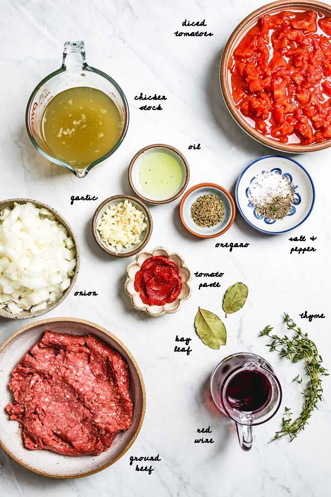 Pasta Bolognese Ingredients for this recipe are placed on a marble and photographed from the top view