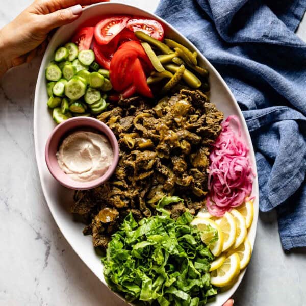 Beef shawarma platter being served by a person from the top view.